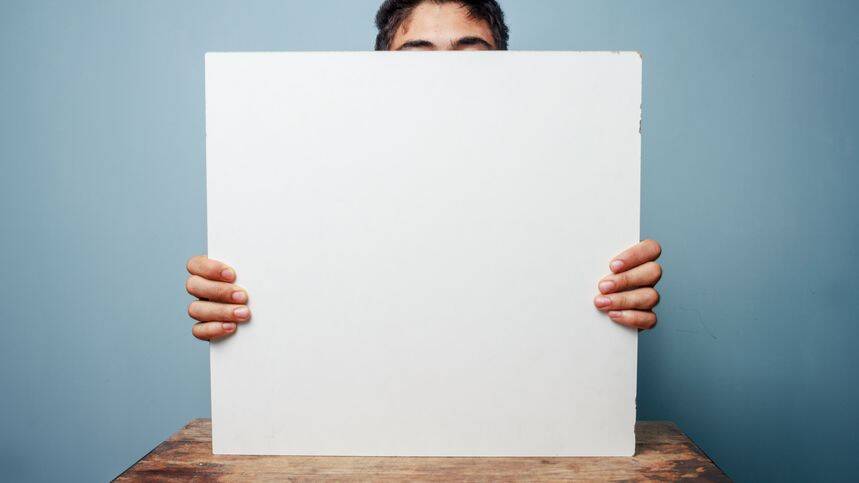A person holding a blank whiteboard, partially obscuring their face, ready for a presentation.