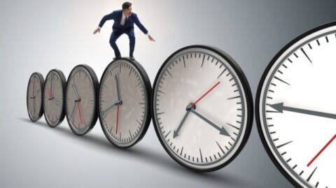 Geschäftsmann, der auf einer Uhr balanciert, als Symbol für Zeit, Druck und die Flucht vor der Bankenpolitik