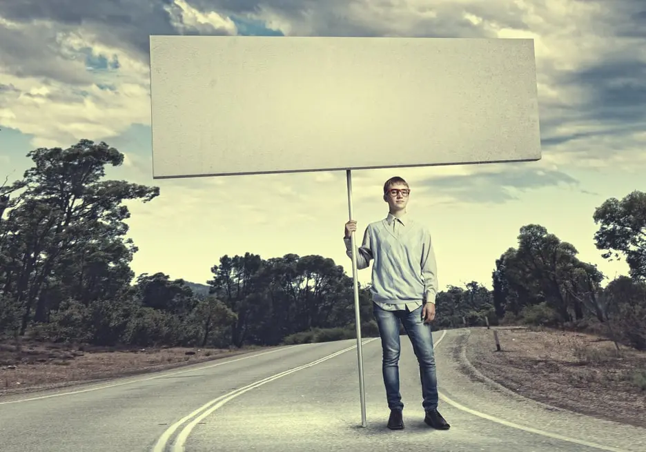 Eine Person hält ein grosses, leeres Schild auf einer leeren Strasse, das für Möglichkeiten und Strategien in der Werbung für Vermögensverwaltung steht.