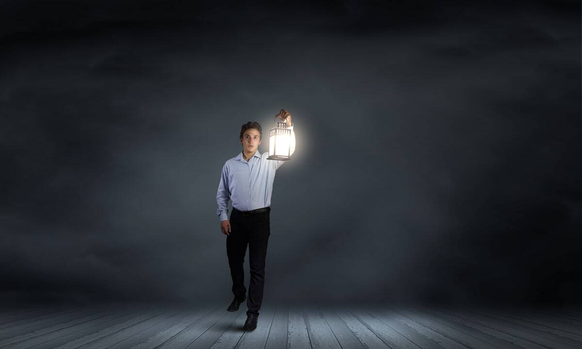 A professional man in a shirt holding a glowing lantern, symbolising guidance and direction in a wealth management career.