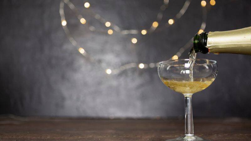 Champagne being poured into a glass with festive lights in the background, symbolizing celebration and achievements. A Year of Challenges