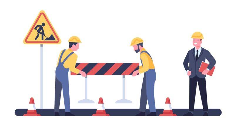 Construction workers setting up road barriers while a supervisor oversees, symbolising financial regulations and compliance in cross-border transactions.