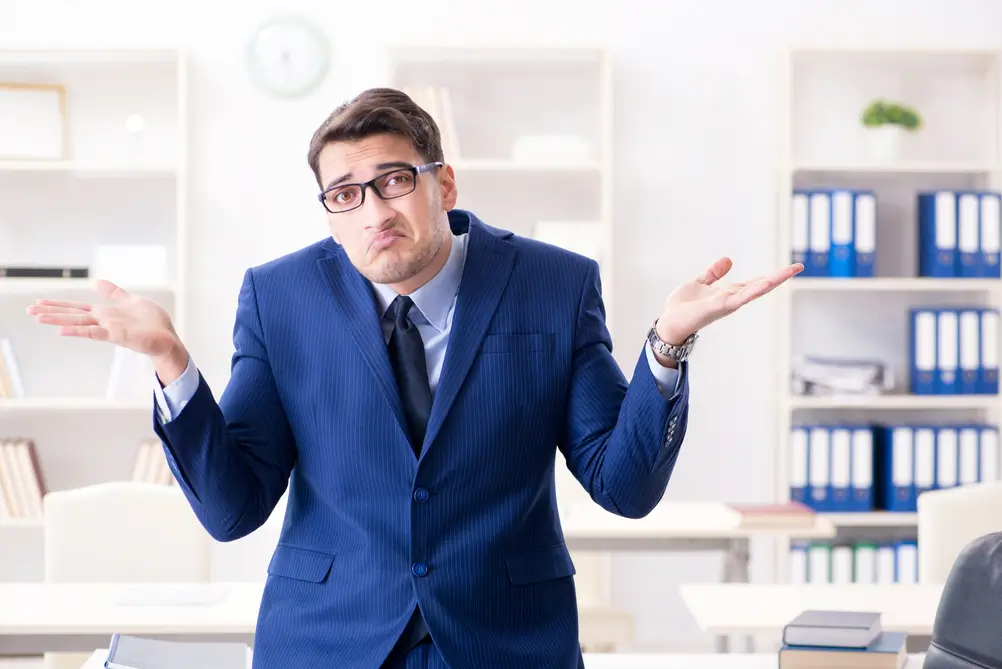 Confused businessman in a suit shrugging, symbolizing the dilemma of choosing between BWL or VWL for a Private Banking career.