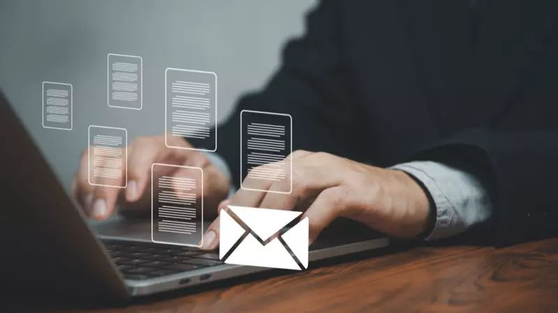 Ein Profi tippt auf einem Laptop mit digitalen E-Mail-Symbolen, die moderne Kommunikationstechnologie, KI und Blockchain-Lösungen repräsentieren.